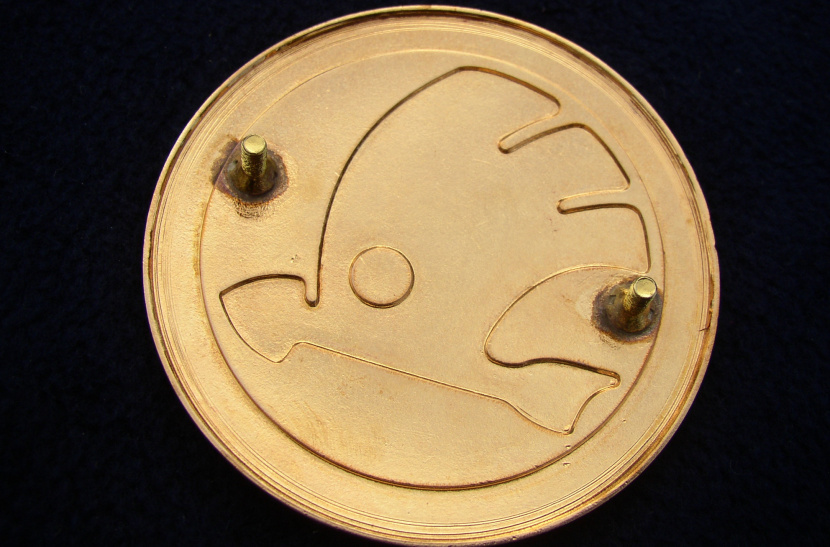 smaltovaný znak ŠKODA (okrídlený šíp)